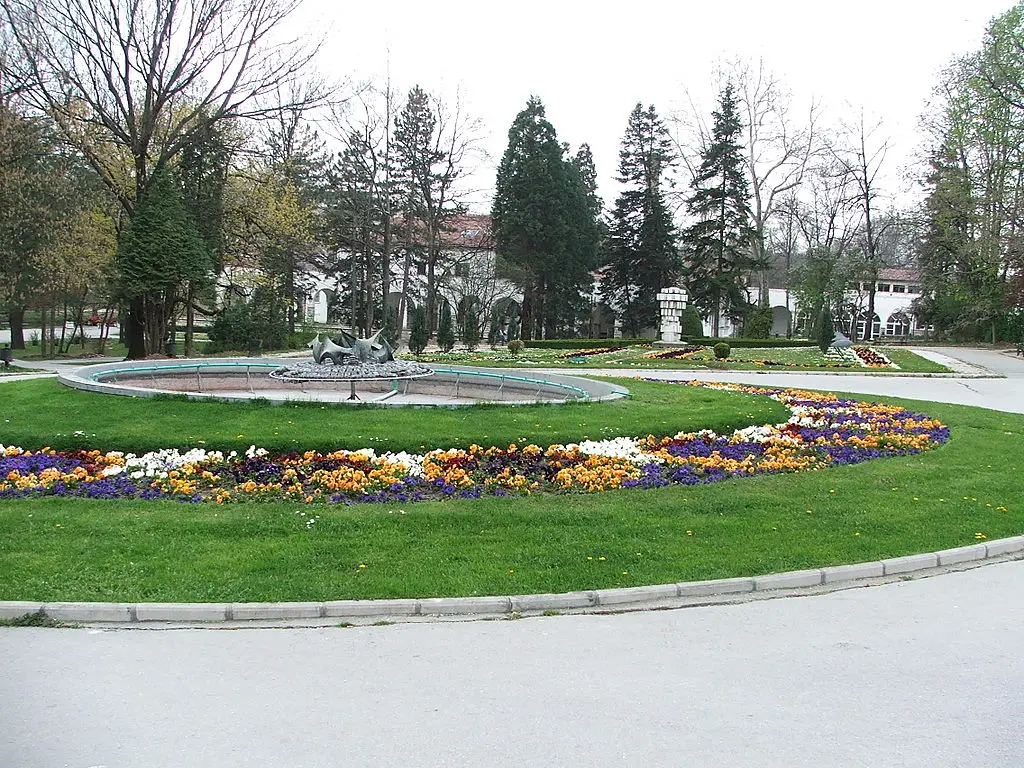 View of Bukovička Banja park in Serbia, featuring walking paths, greenery, and benches.