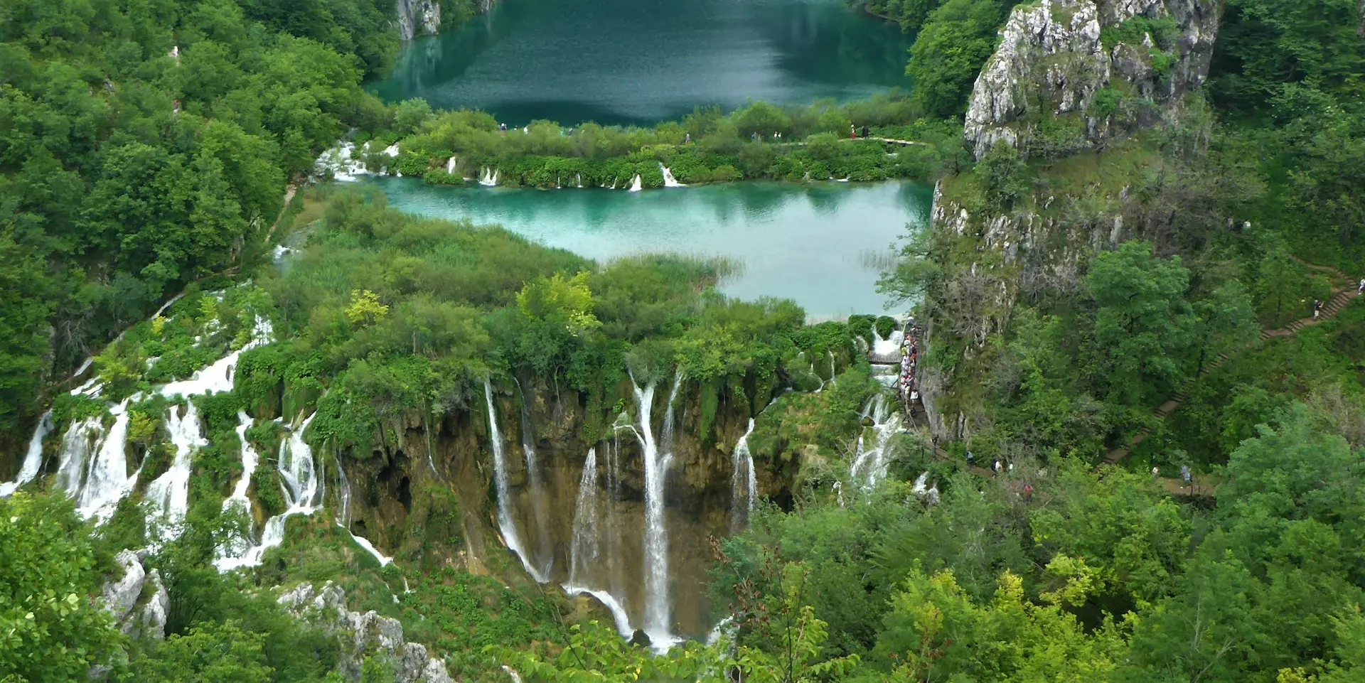 Aerial view of Plitvice Lakes waterfalls and turquoise lakes surrounded by lush forests.